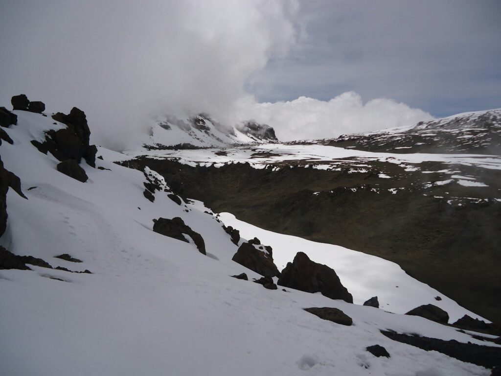 a mountain covered in snow with a cloud in the sky